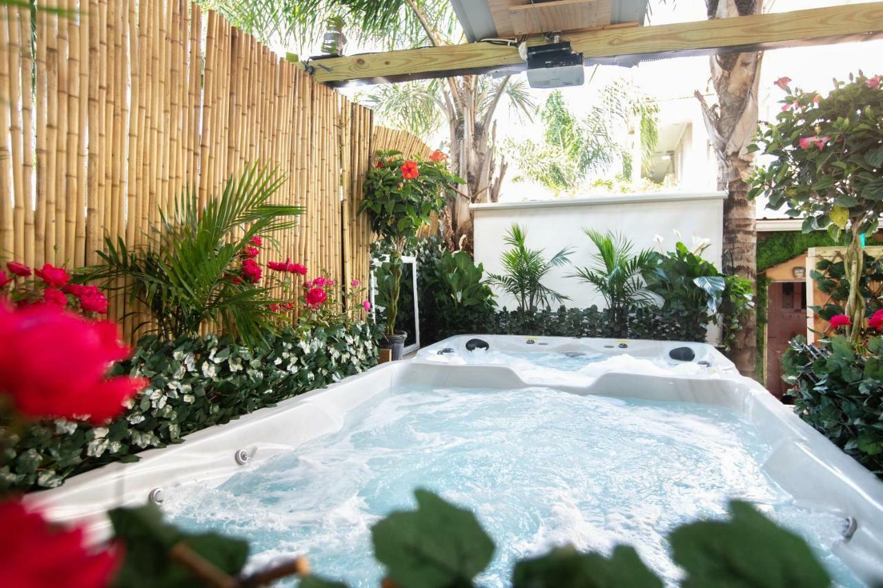 A white hot tub with bubbles surrounded by plants and flowers in a fenced-in area.